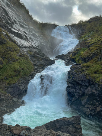 Kjoasfossen Waterfall, Norway cascades down rugged rocks surrounded by lush greenery, creating mist and frothy whitewater. Steep, rocky powerful Norwegian waterfall.の写真素材