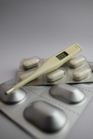 white pills in blister pack with thermometer on white background, medicineの写真素材