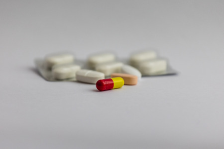 pills in different colors and a blister pack on white background, medicine