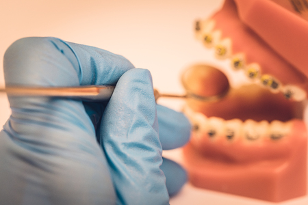 Detailed close up of dental instrument working on a denture or teeth, blue rubber glove dentistry