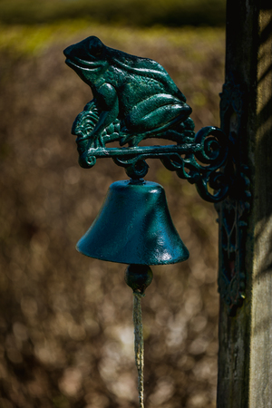 green frog figure with a bell on a garden door in germanyの写真素材