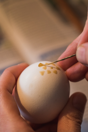 Detailed macro shot of woman, handpainting an easter egg with wax, germanyの写真素材