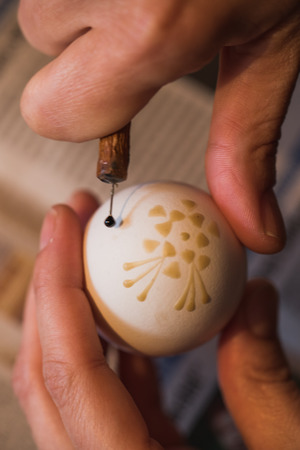 Detailed macro shot of woman, handpainting an easter egg with wax, germanyの写真素材