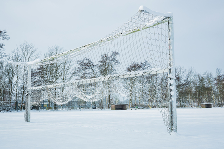 Snow covered soccer field with goal during winterの写真素材