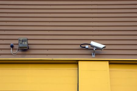 A security camera and a spot light on a warehouse