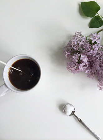 Milk pouring into coffee with sugar spoon and fresn lilac flowersの写真素材