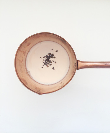 Lavender buds steeping in milk in a copper potの写真素材