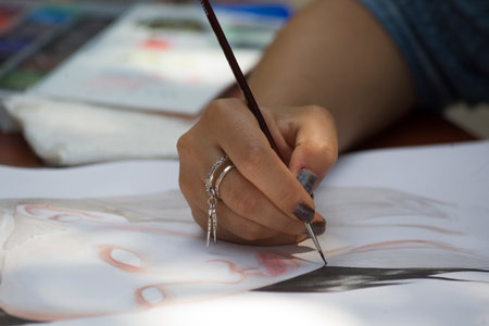 Close-up of a girl's hand drawing a picture on the paper