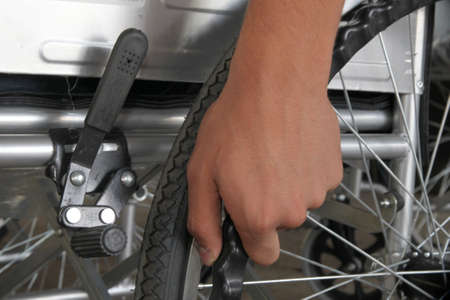 Close up of a male hand holding a wheel of a wheelchair.
