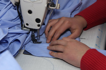 Close-up of a woman's hand sewing on a sewing machine