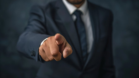 Businessman pointing his finger at the camera on a dark background.の写真素材