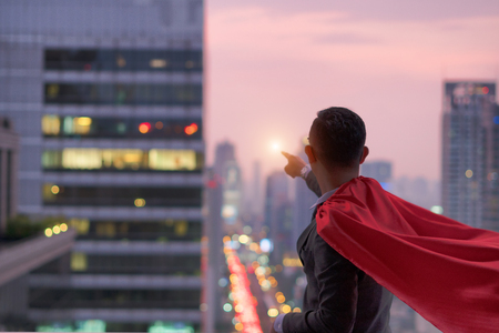 superhero businessman looking at city skyline at sunset. the concept of success, leadership and victory in business.の写真素材