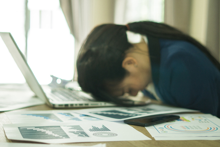Blurry stressed business woman working on a laptopの写真素材