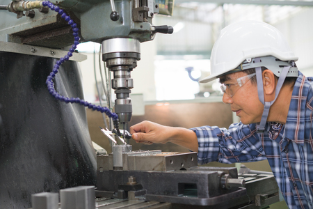 Employee drilling in flat steel plate with bench drill.の写真素材