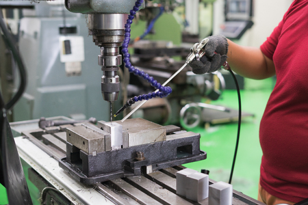 Employee drilling in flat steel plate with bench drill.の写真素材