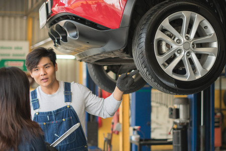 A mechanic showing the tread of a tire to a female customerの写真素材