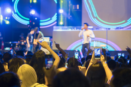 Audience recording video of band on mobile phone in concert.