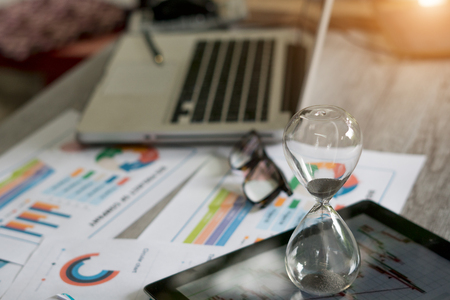 An hourglass on a tabletop on a business desk.の写真素材