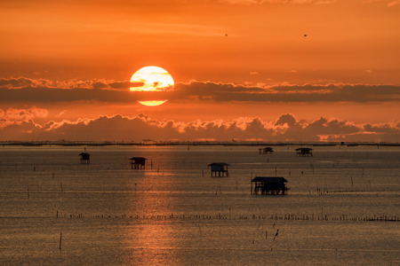 sunrise over lake with silhouette fishing house on foreground.の写真素材