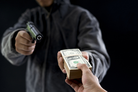 Robbery with gun's. Gun and money in a hands. Bank robbery, Man carrying a gun to rob the bank note. To threaten with the man. A murderer attacking holding gun kidnapping business young person.の写真素材