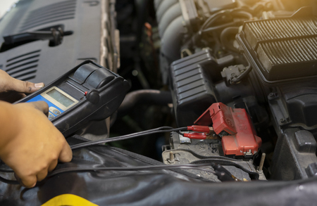 mechanic use voltmeter checking voltage of car battery in car service centreの写真素材