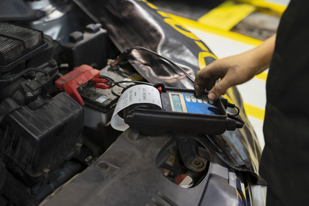 mechanic use voltmeter checking voltage of car battery in car service centre