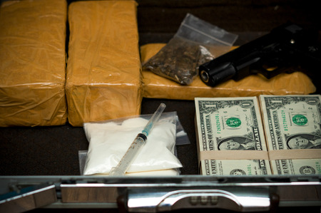 Drug trafficker holding a lot of cash on hand and use gun pushing drugs to the customer in the Drug dealing, concept about the drug problemの写真素材