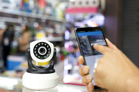 Close-up Of A Person's Hand Holding Mobile Phone With CCTV Camera Footage On Screenの写真素材
