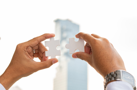Closeup hand of woman connecting jigsaw puzzle with sunlight effect, Business solutions, success and strategy conceptの写真素材