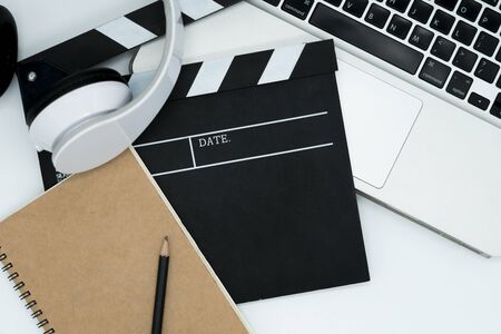 Movie maker with movie editing device,laptop, earphone, movie clapper board, note pad on white background.の写真素材