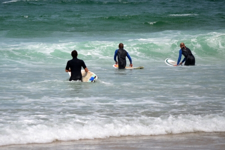 Three professional surfers on the way to catch the waves