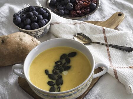 Sweet potato and carrot soup with pumpkin seeds and blueberries as a desertの写真素材