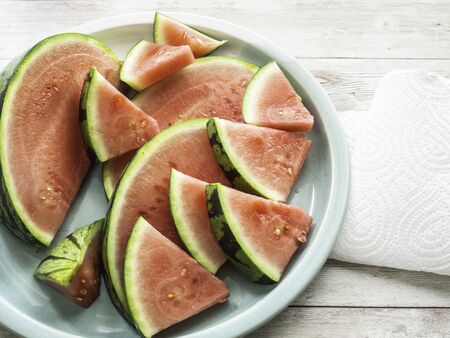 Juicy watermelon sliced on a green plate, white background with copy space, top viewの写真素材