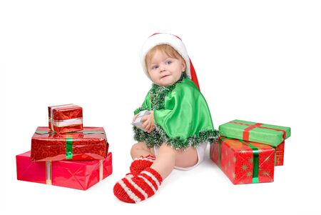 Little girl in Santa hat and green tree suit with New Year s gifts on white.の写真素材