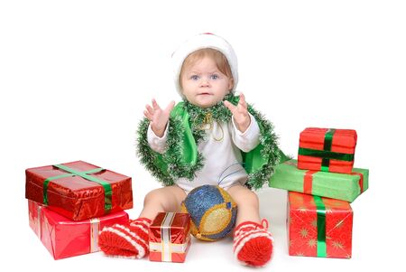 Little girl in Santa hat and green tree suit with New Year s gifts on white.の写真素材
