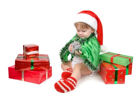 Little girl in Santa hat and green tree suit with New Year s gifts on white.の写真素材