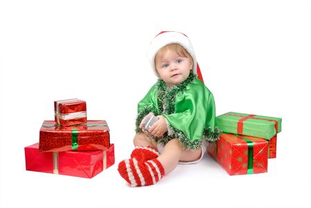 Little girl in Santa hat and green tree suit with New Year s gifts on white.の写真素材