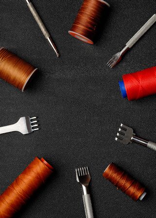 Leather crafting DIY tools and threads lies on natural black leather.の写真素材