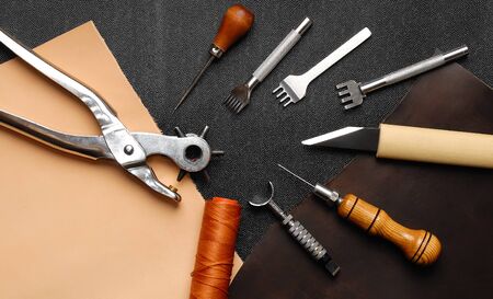 Leather crafting DIY tools lies on natural black and brown leather.の写真素材