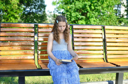 Thoughtful Girl reading a book while sitting on the benchの写真素材