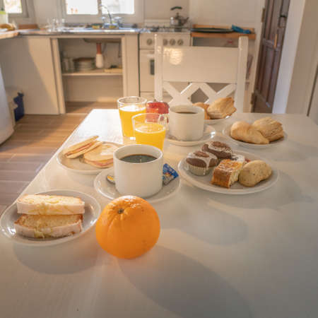 Breakfast with coffee, orange juice and pastries in the kitchenの写真素材