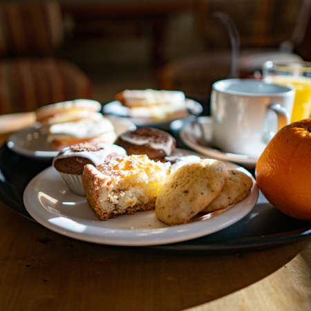 Breakfast with coffee, orange and muffins on a wooden tableの写真素材