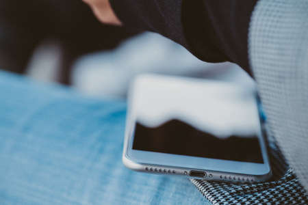 White smartphone resting on a person's legの写真素材