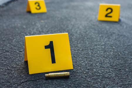 A group of yellow crime scene evidence markers on the street after a gun shooting brass bullet shell casing rifleの写真素材