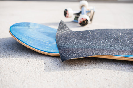 Applying grip tape to a brand new skateboard deck next to a set of trucks and wheelsの写真素材