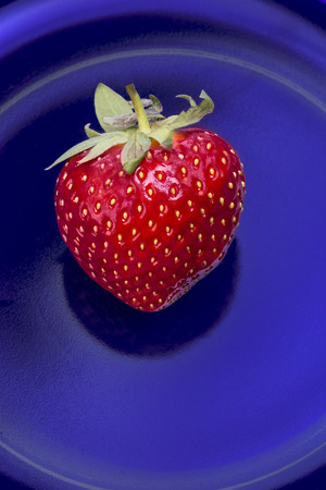 Red strawberry on a blue glass background.の写真素材