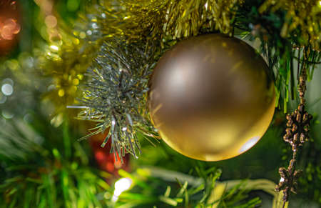 A golden Christmas ornament hanging on a branch of a Christmas tree.の写真素材