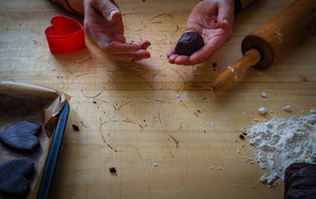 Close up of female hands making gingerbread cookies on wooden table.の写真素材