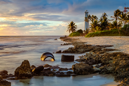 Beautiful Barbers Point Lighthouse seascape, long exposure during sunset on the rocky coastline of Oahu, Hawaii, USA.の写真素材