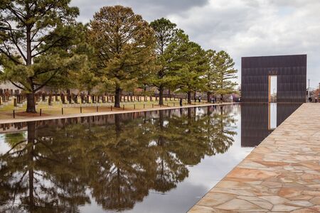 OKLAHOMA CITY, OKLAHOMA / USA - MARCH 31, 2018: People walking around and visiting the OKC Bombing Memorial and reflect in the shallow pool.のeditorial素材